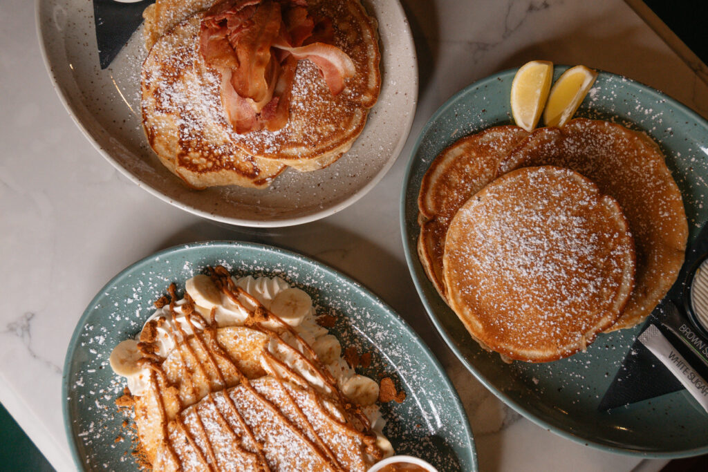 Three delicious pancakes with popular toppings: lemon and sugar, maple syrup with crispy bacon, and biscoff spread with banana slices, perfect for Pancake Tuesday in Limerick at The Old Quarter.